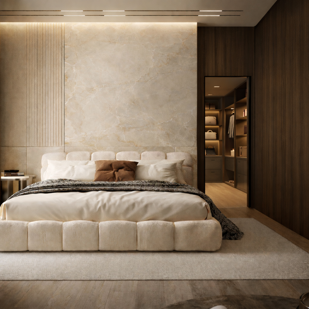 Chambre avec lit rembourré clair, mur à l’aspect minéral et panneaux en bois sombre ouvrant sur un dressing éclairé.